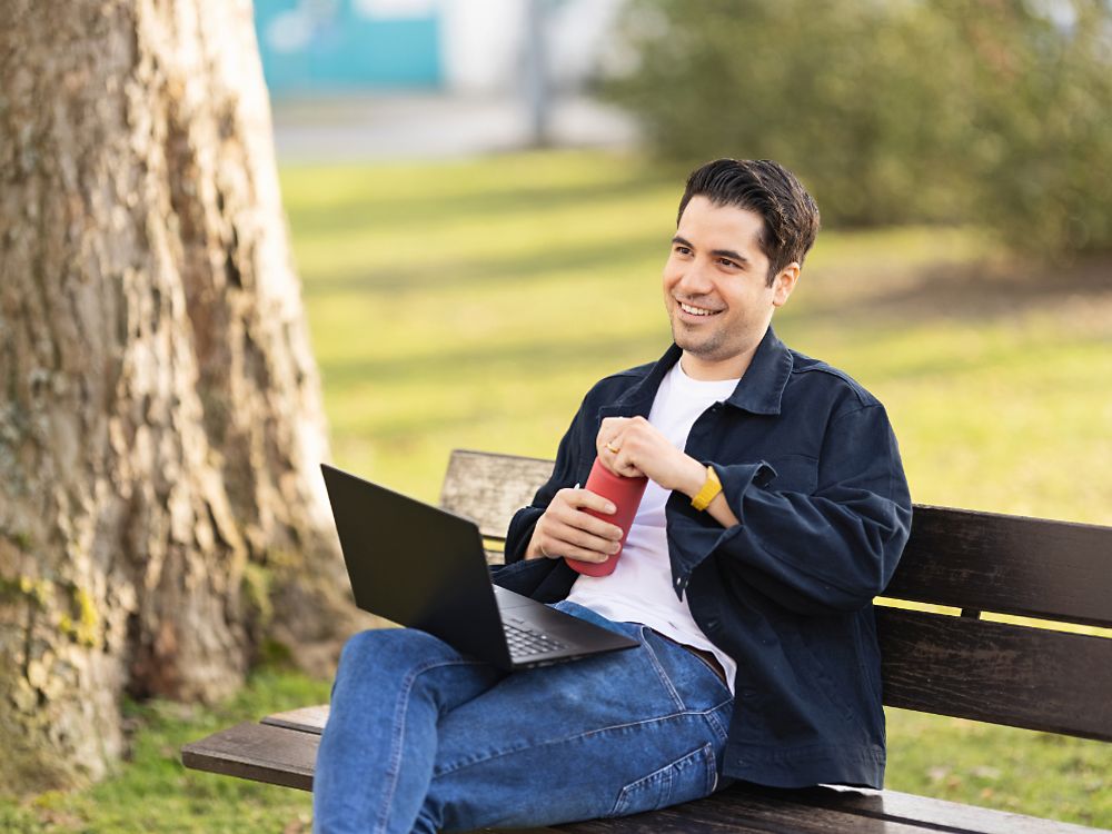 한 헨켈 직원이 공원 벤치에 앉아 노트북 작업을 하고 있습니다. 