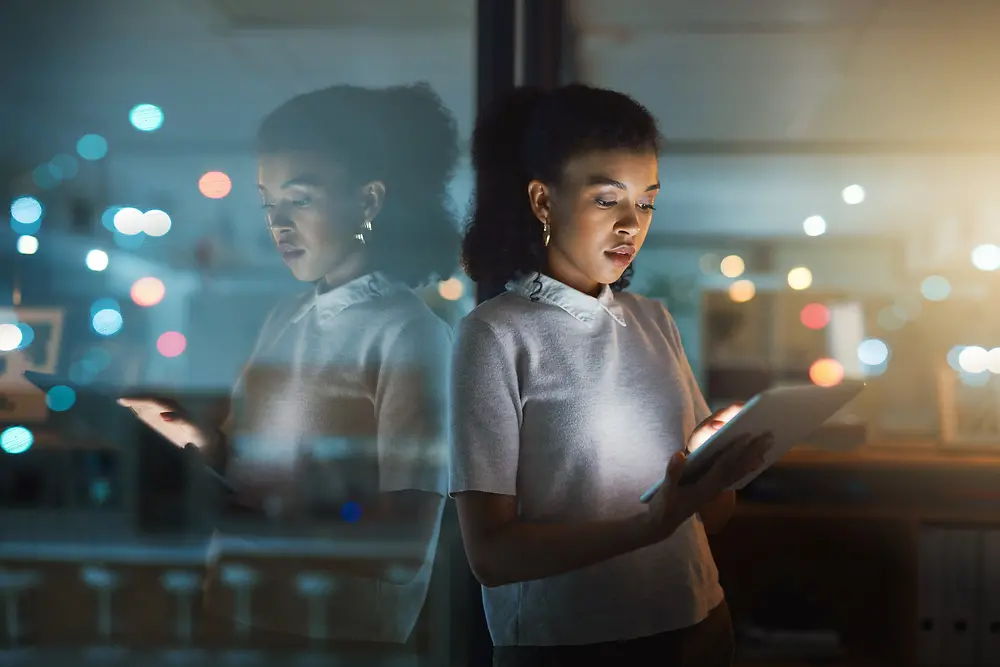 A woman is typing on a tablet, looking focused and concentrated.