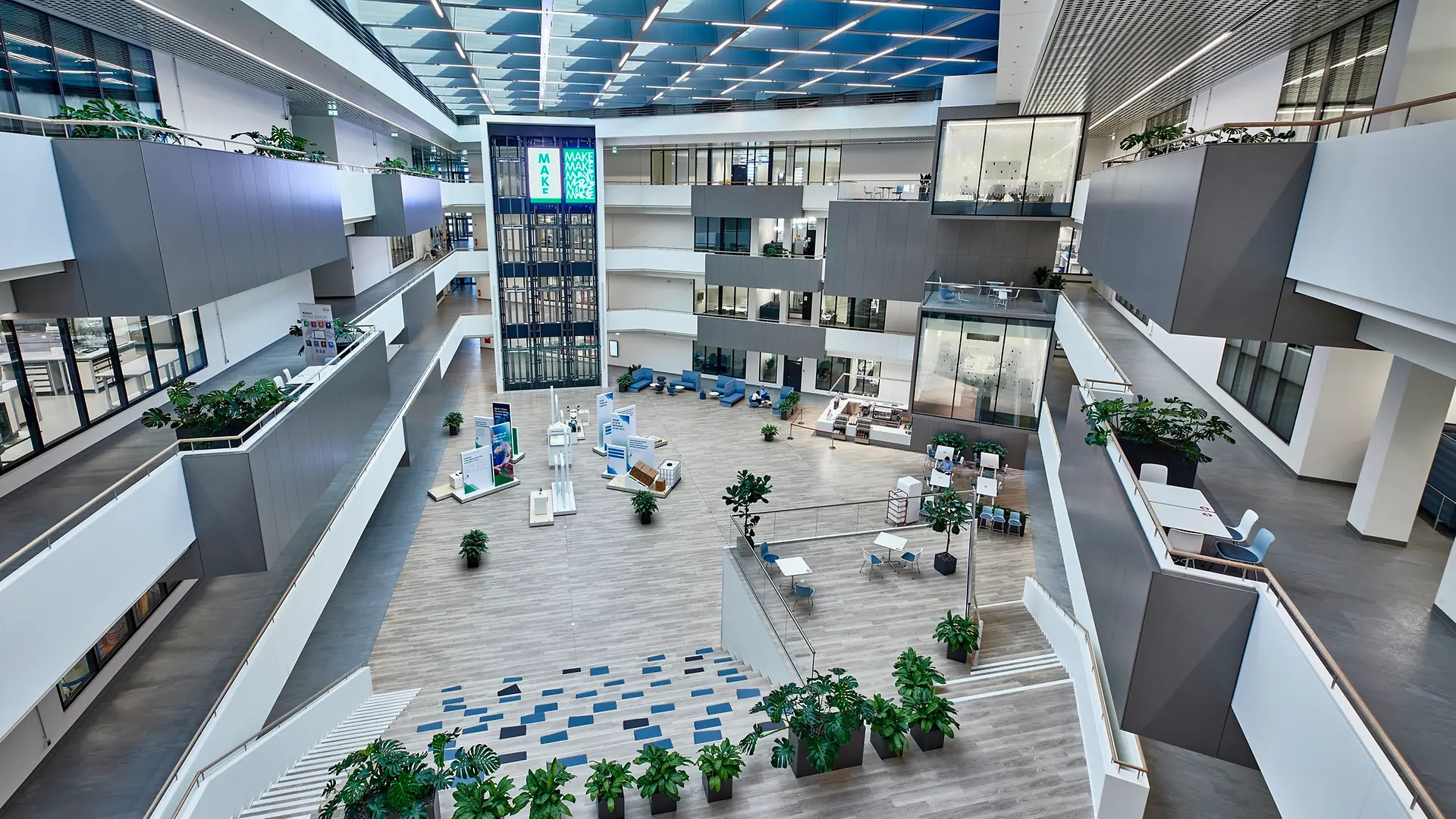 중앙에 대형 안뜰이 자리한 인스피레이션 센터 뒤셀도르프 내부 전경으로, 총 4개 층에 걸쳐 유리 외벽의 첨단 연구실이 보입니다.