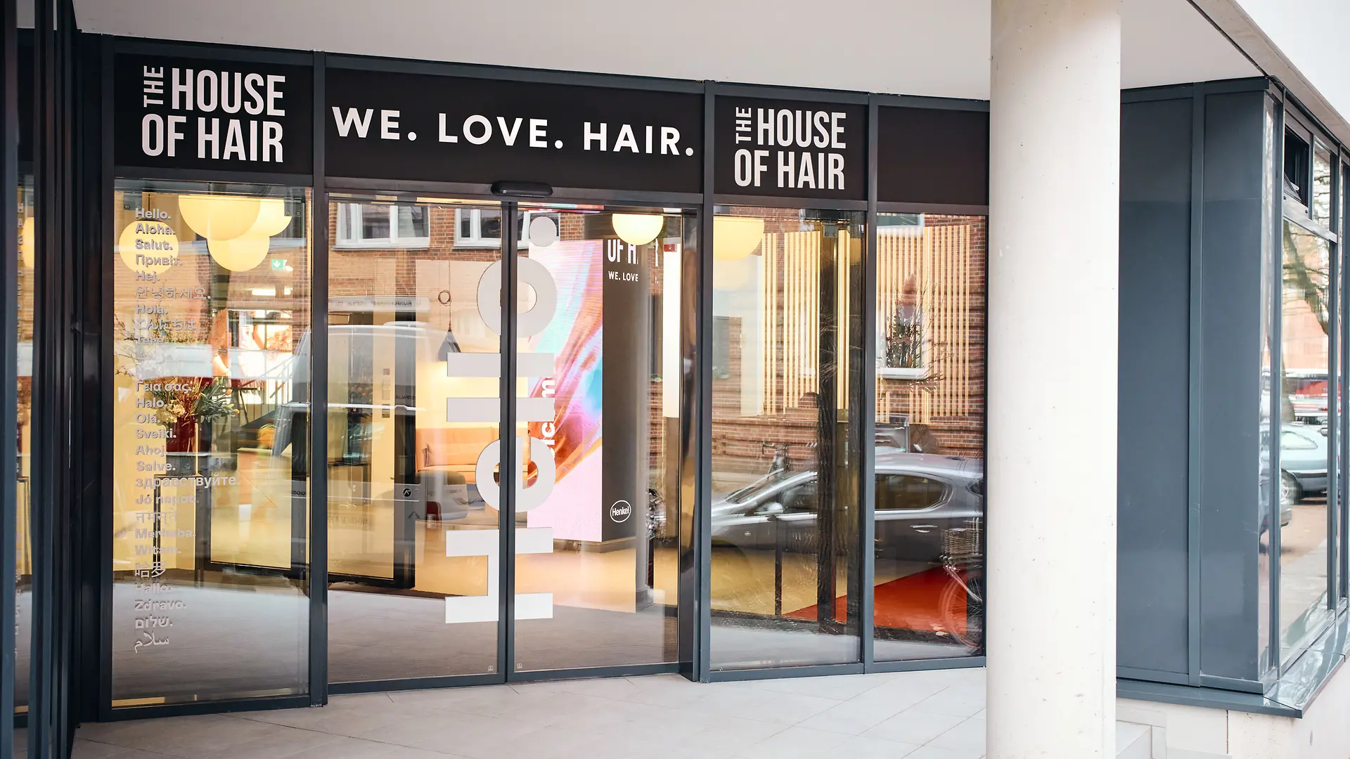 유리로 된 입구 위에는 “We. Love. Hair.”라는 문구가, 좌우에는 “The House of Hair”라는 명칭이 표시되어 있습니다.