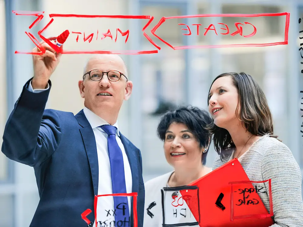 Employees writing on glass board.